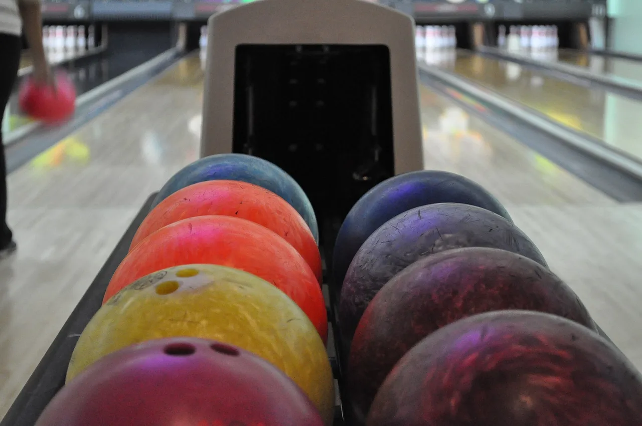 Colorful bowling balls on a return rack beside bowling lanes