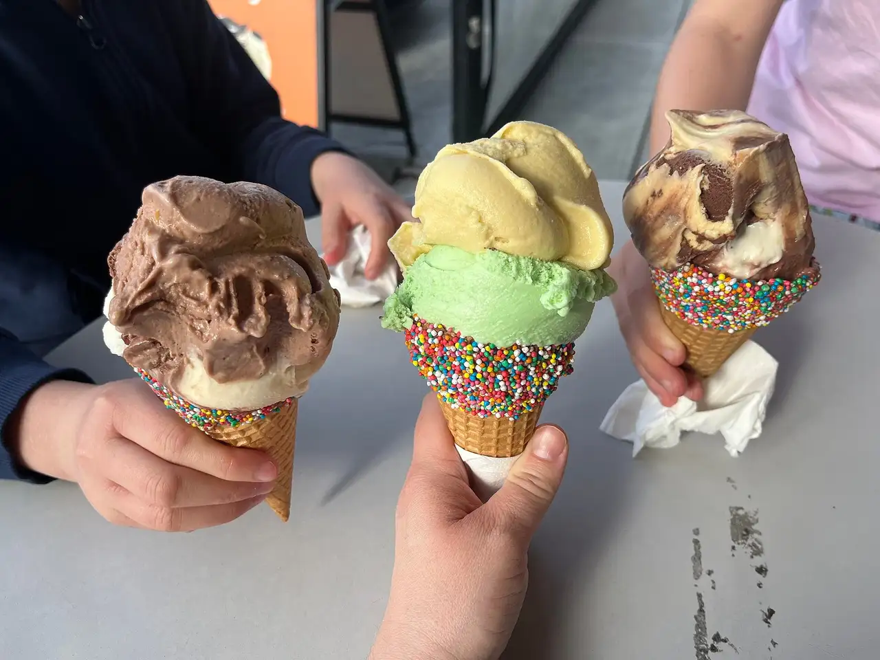 Three colorful ice cream cones with sprinkles, an illustrative dessert photograph